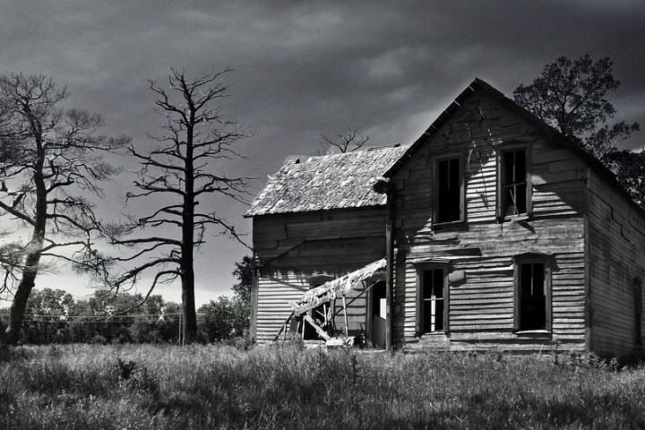 an abandoned house surrounded by grass field